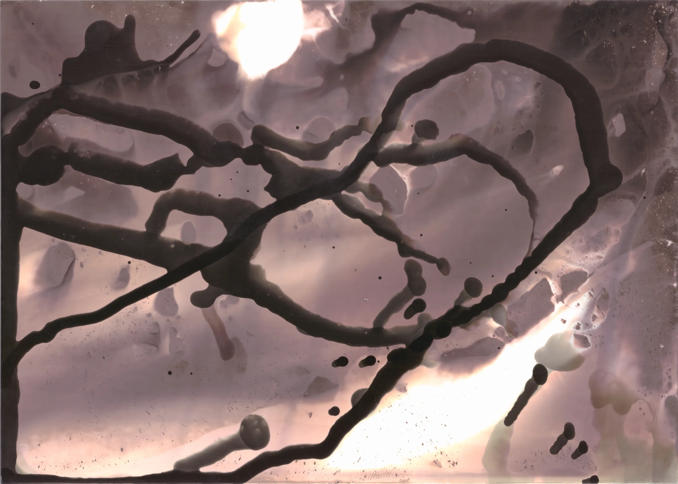 Looping dark drips over a pale, pitted surface