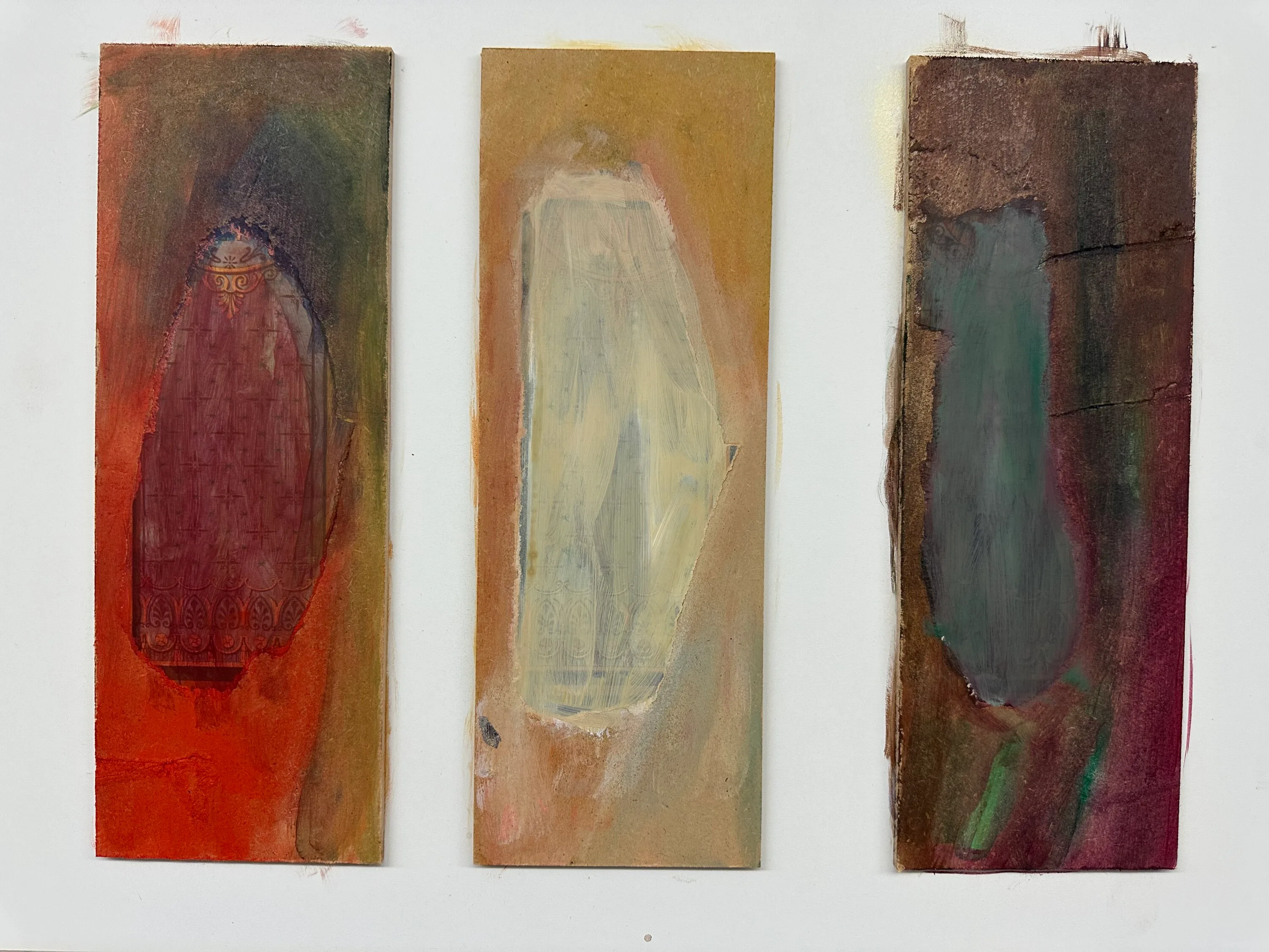 Three narrow upright panels side by side, each holding one soft oval: dark red on orange, pale cream on ochre, grey-green on brown